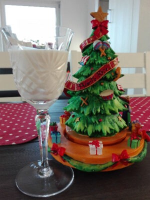 Photo of a glass of coquito next to an ornament in the shape of a Christmas tree with a ribbon that reads: Puerto Rico