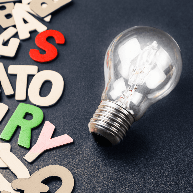 Photo of a bright lightbulb next to wooden letters that spell STORY