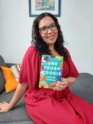 Author Delise Torres holding her debut novel, One Tough Cookie