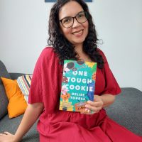 Author Delise Torres holding her debut novel, One Tough Cookie